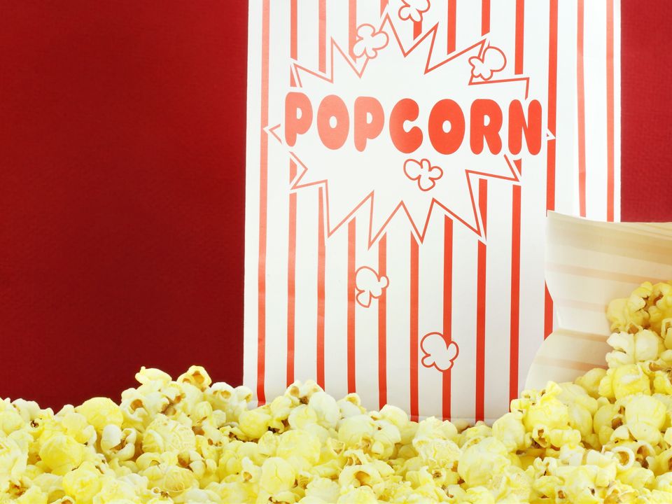 Bags of buttery popcorn against a red background. Room for text.